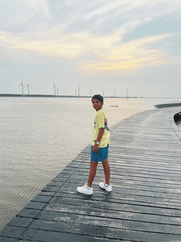 Dev Sanghavi walking along a wooden boardwalk by the water
